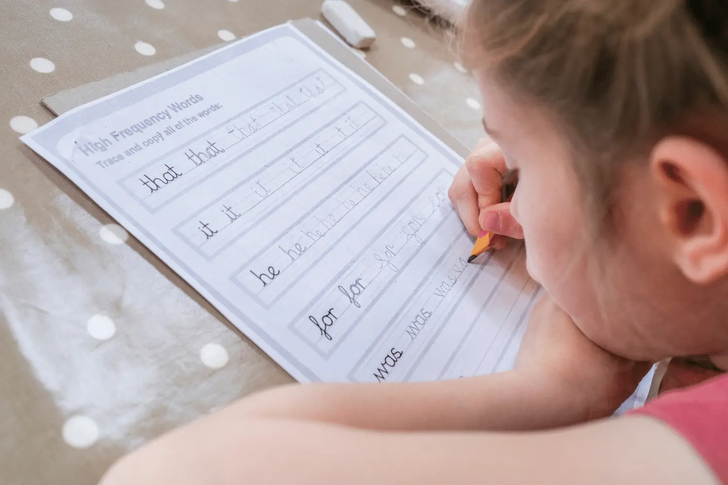 Child writing a postcard at a kitchen table with a parent helping — home handwriting activity